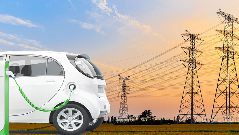 Ein Elektroauto wird an einer Ladesäule geladen. Im Hintergrund sind Strommasten zu sehen.